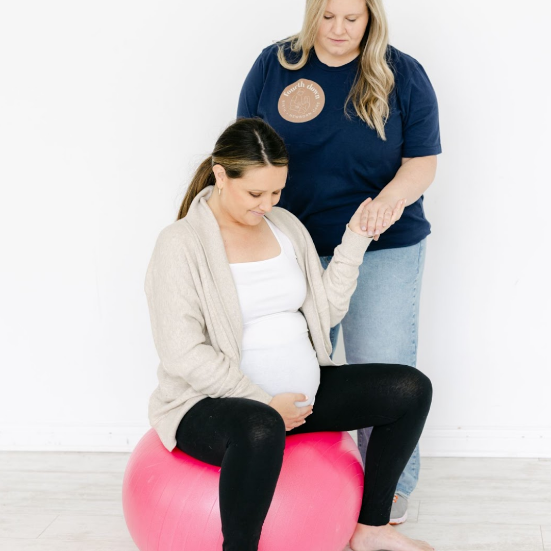 pregnant woman on yoga ball being held by a caretaker