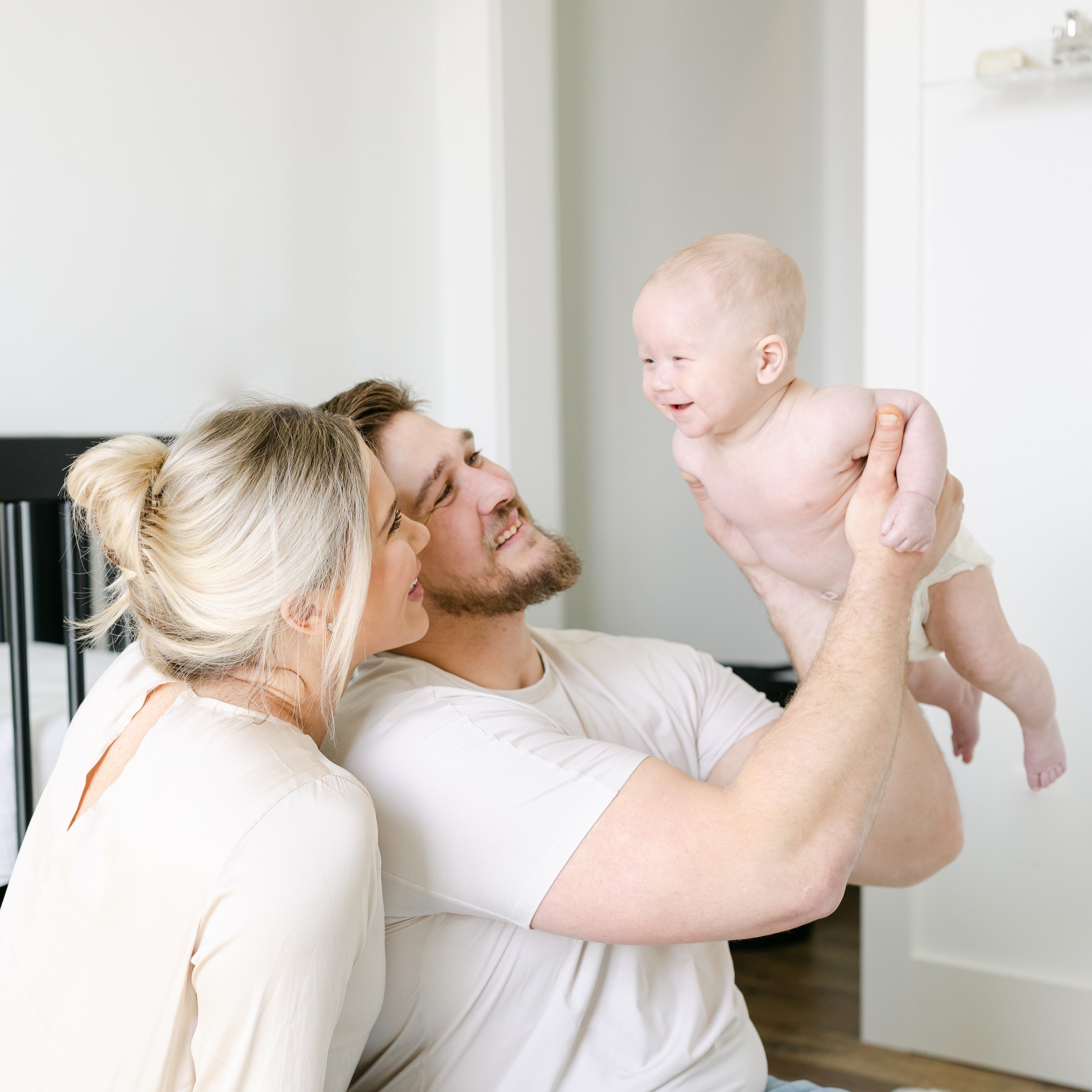 man and woman holding their baby in the air